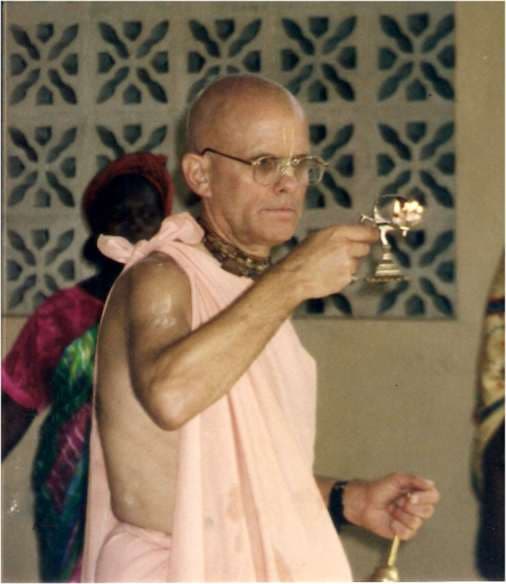 Mahavishnu Swami offering aarati with a lamp and bell
